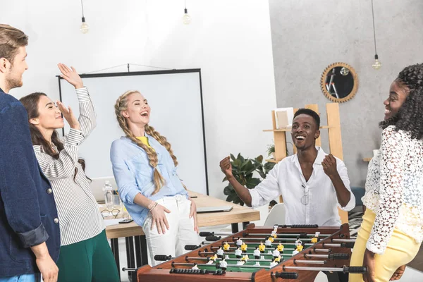 Colegas multiculturales jugando al futbolín - foto de stock