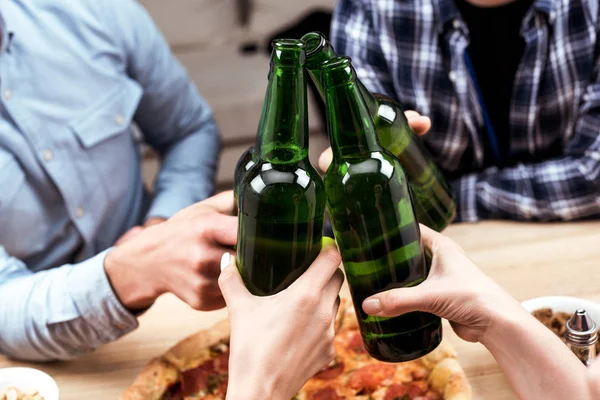 Amigos tintineo botellas de cerveza - foto de stock