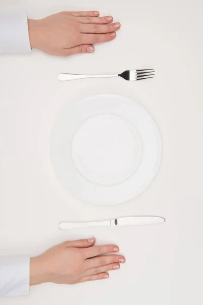 Руки, пустая тарелка и столовые приборы — стоковое фото