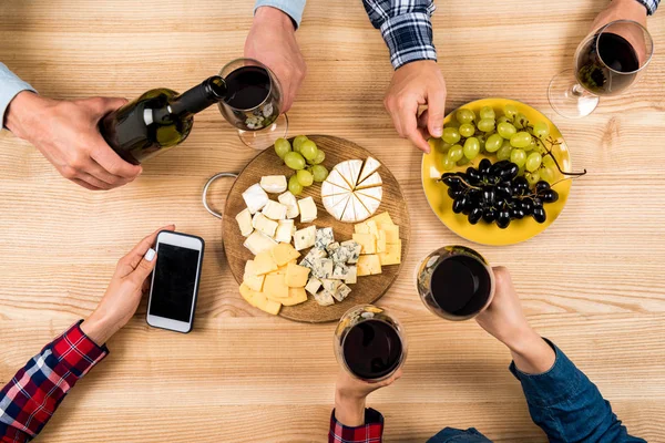 Amigos comiendo queso y bebiendo vino - foto de stock