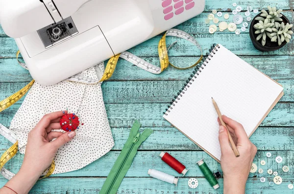 Alfaiate com caderno e alfinetes no local de trabalho — Fotografia de Stock