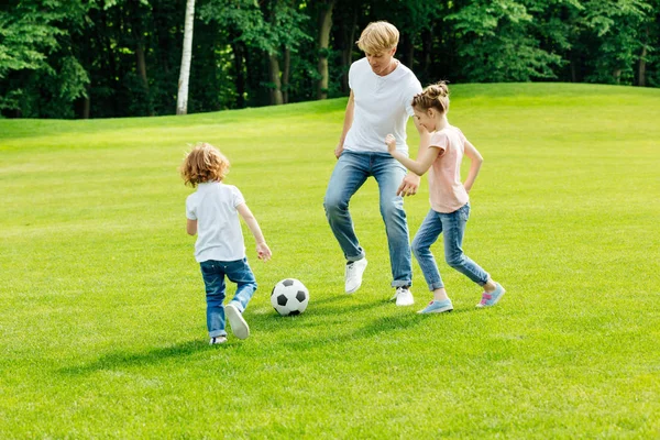 Padre con niños jugando al fútbol en el parque - foto de stock