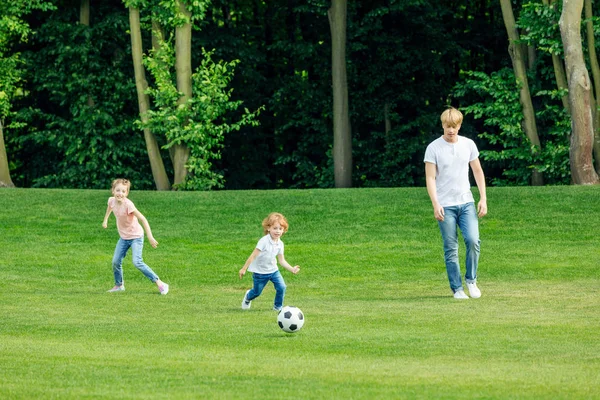 Pai com crianças jogando futebol no parque — Fotografia de Stock