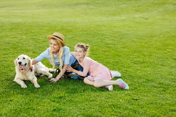 Madre e hija con perro en el parque - foto de stock