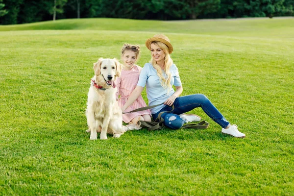 Madre e hija con perro en el parque - foto de stock