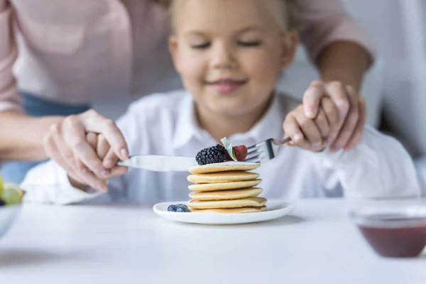 Madre e hija comiendo panqueques - foto de stock