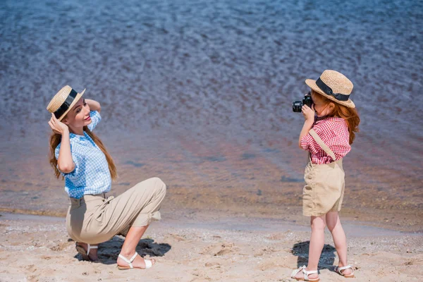 Ребенок фотографирует мать у моря — стоковое фото
