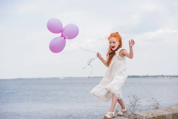 Child with balloons on quay — Stock Photo