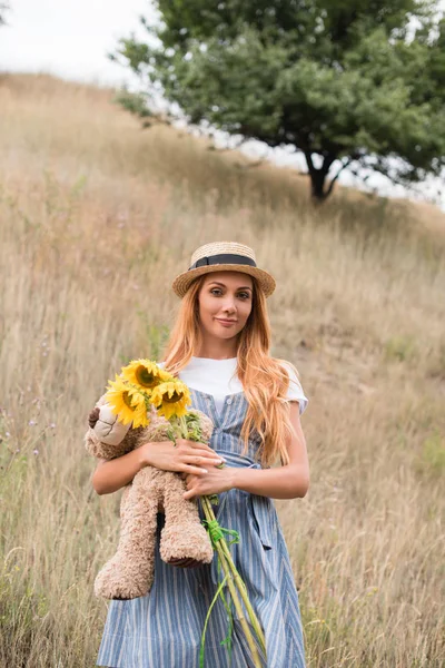 Girl with teddy bear and sunflowers — Stock Photo