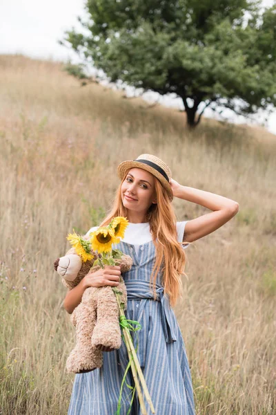 Girl with teddy bear and sunflowers — Stock Photo