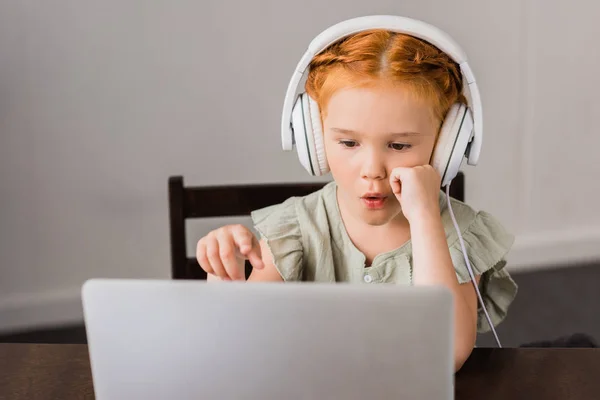 Little girl with headphones and laptop — Stock Photo