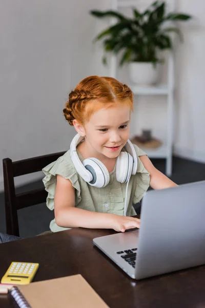 Маленькая девочка с наушниками и ноутбуком — стоковое фото