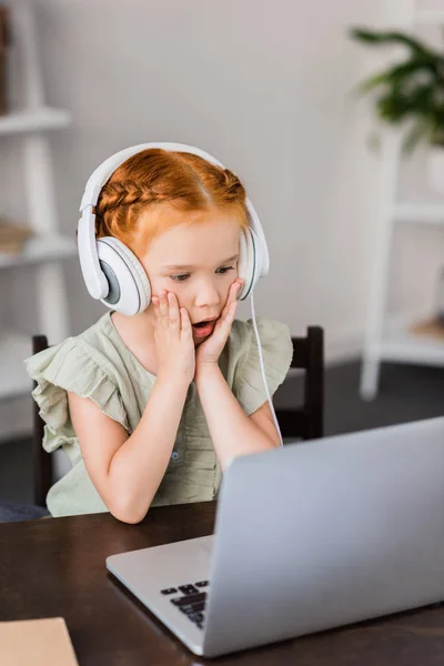 Petite fille avec écouteurs et ordinateur portable — Photo de stock