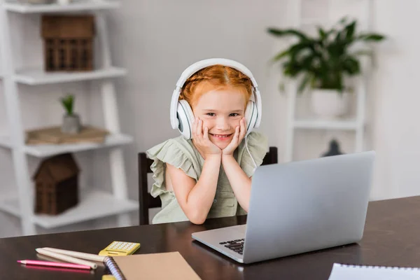 Niña con auriculares y portátil - foto de stock