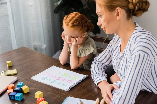 Madre e hija deprimida aprendiendo matemáticas - foto de stock