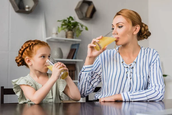 Madre e hija bebiendo jugo de naranja - foto de stock