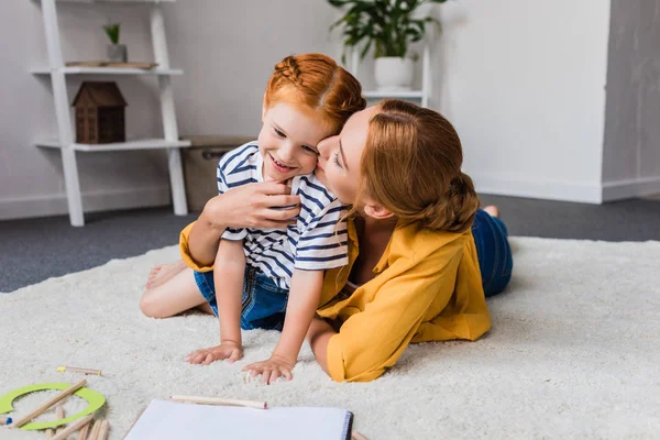 Madre besando a su hija en la mejilla - foto de stock