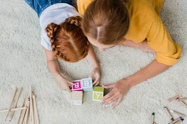 Mother and daughter playing with letter cubes — Stock Photo