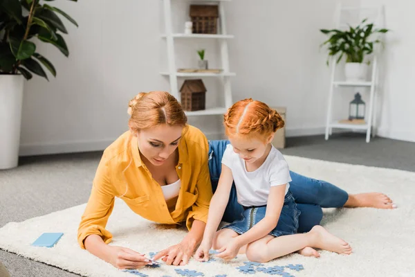 Mother and daughter assembling puzzle — Stock Photo