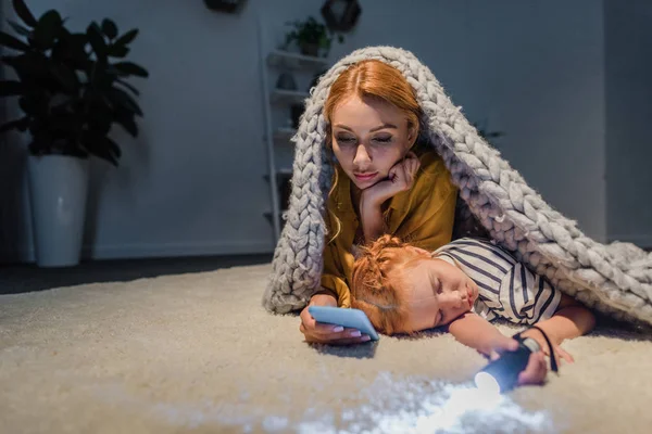 Hija durmiendo blanco madre usando smartphone - foto de stock