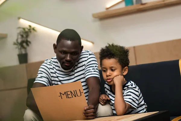 Padre e figlio afroamericano con menu — Foto stock
