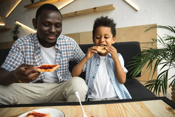 Padre e hijo comiendo tostadas - foto de stock