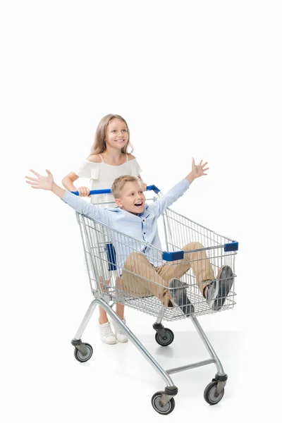 Sister riding brother in shopping cart — Stock Photo
