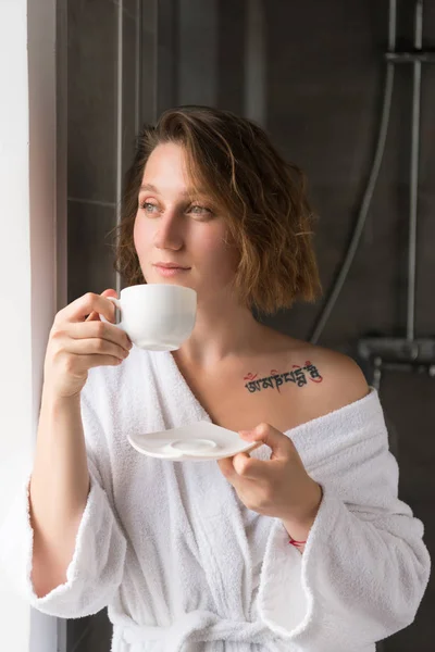 Girl in bathrobe drinking coffee — Stock Photo