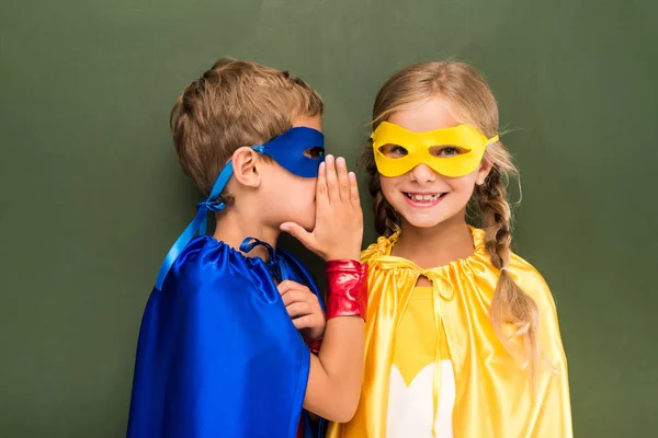 Gossiping pupils in superhero costumes — Stock Photo