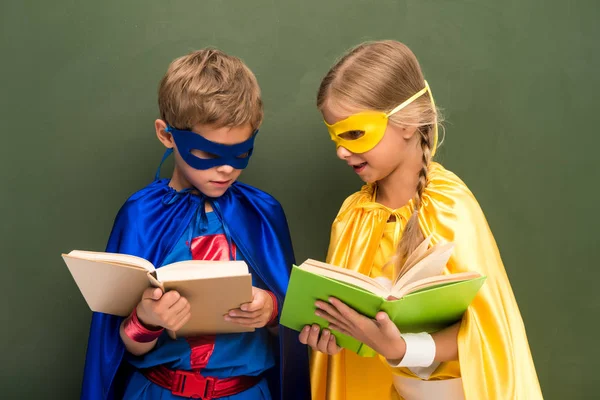 Alumnos en trajes de superhéroes con libros - foto de stock