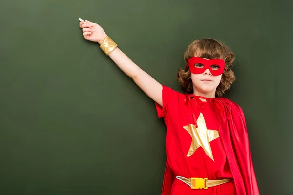 Superhero pointing on chalkboard — Stock Photo