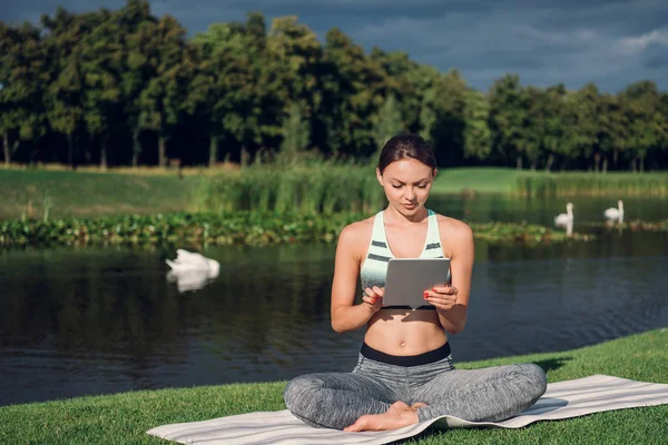 Mujer practicando yoga con tableta - foto de stock