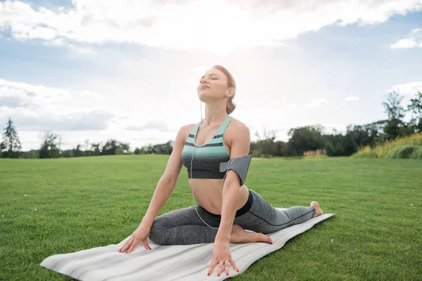 Mujer en auriculares practicando yoga - foto de stock