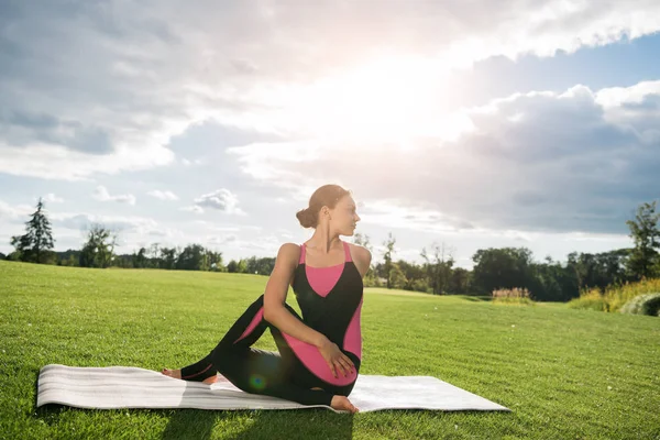 Женщина, сидящая в позе йоги в парке — стоковое фото