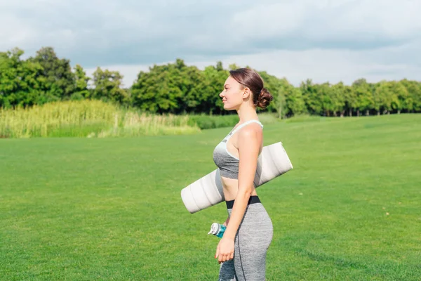 Женщина с ковриком для йоги и бутылкой воды — стоковое фото