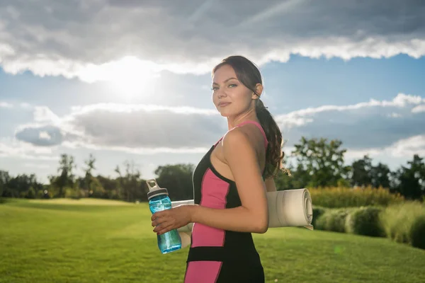 Mujer con esterilla de yoga y botella de agua - foto de stock