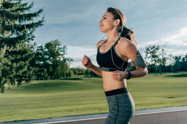 Sportive running woman in earphones — Stock Photo