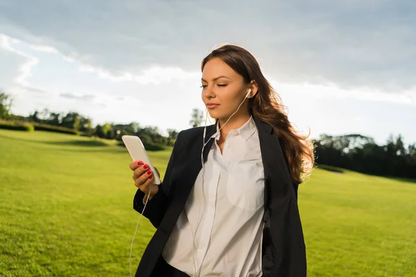 Geschäftsfrau mit Kopfhörer und Smartphone — Stockfoto