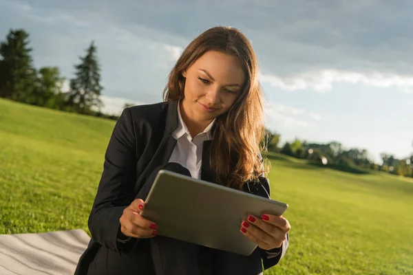 Mujer de negocios con tableta en césped verde - foto de stock