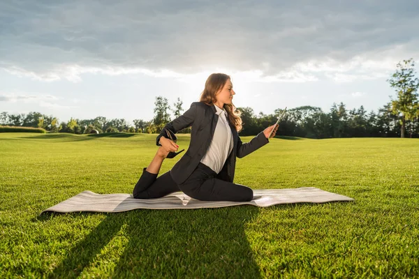Empresaria practicando yoga con tablet - foto de stock