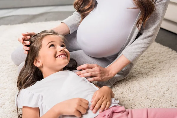 Schwangere mit Tochter sitzt auf Teppich — Stockfoto