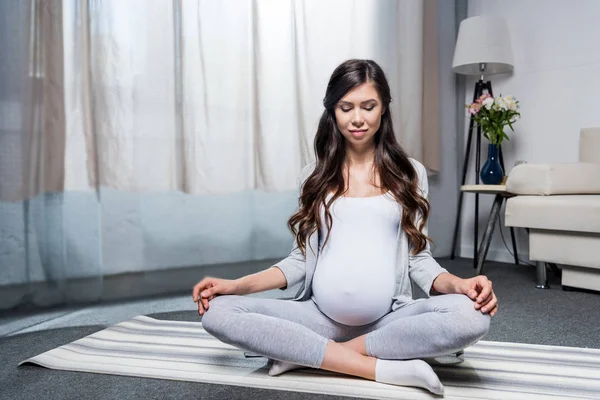 Mujer embarazada sentada en pose de loto - foto de stock