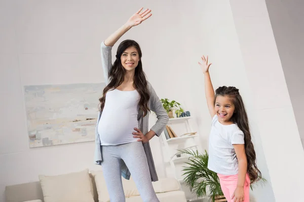 Mujer embarazada y su hija haciendo ejercicio - foto de stock