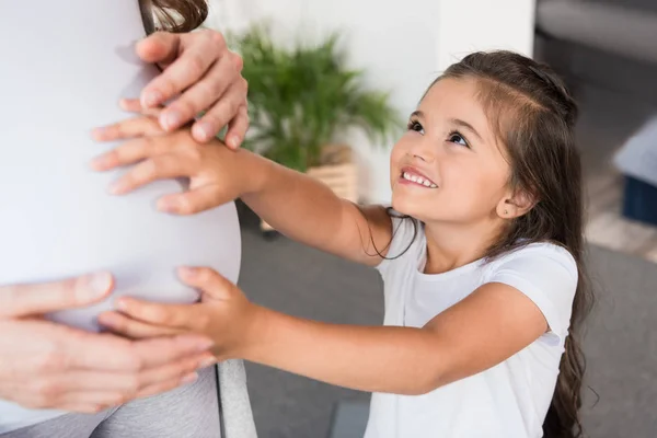 Маленькая девочка трогает беременный живот — стоковое фото