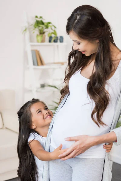 Petite fille touchant ventre enceinte — Photo de stock