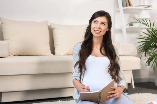 Mujer embarazada escribiendo en cuaderno - foto de stock