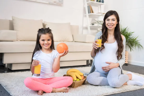 Donna incinta e figlia con bicchieri di succo — Foto stock