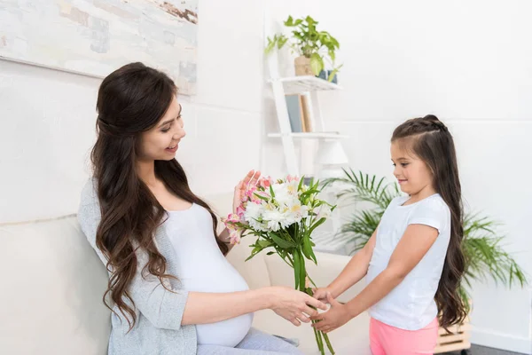 Chica dando ramo a la madre embarazada - foto de stock