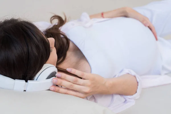 Mulher grávida em grandes fones de ouvido — Fotografia de Stock