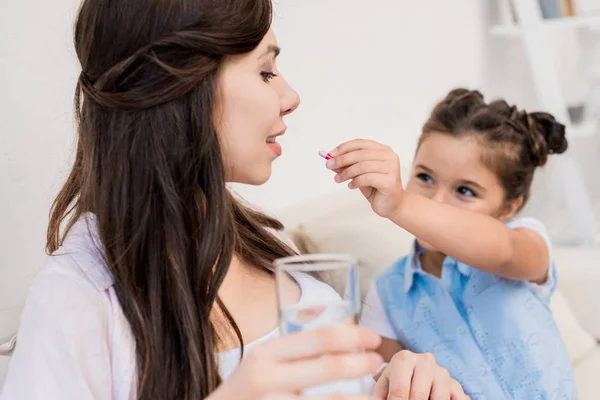 Girl feeding pill to mother — Stock Photo